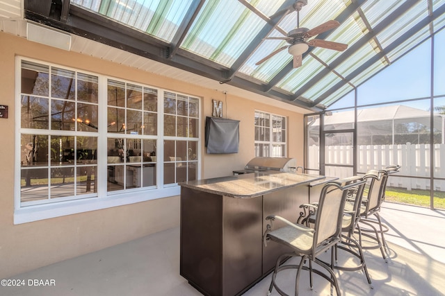 view of patio / terrace featuring ceiling fan, a lanai, exterior bar, and exterior kitchen