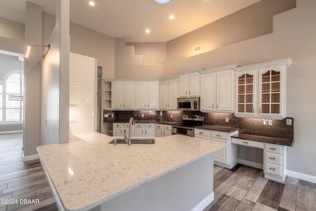 kitchen with white cabinetry, sink, light stone counters, appliances with stainless steel finishes, and dark hardwood / wood-style floors