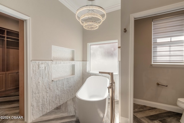 bathroom with toilet, a tub, an inviting chandelier, hardwood / wood-style floors, and ornamental molding