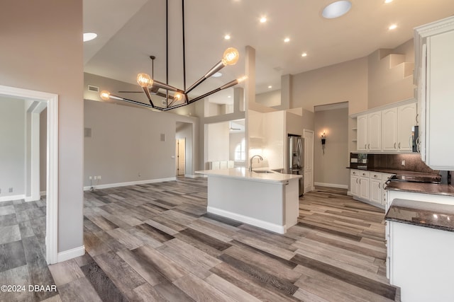 kitchen with stainless steel appliances, light hardwood / wood-style floors, white cabinets, a kitchen island, and a high ceiling