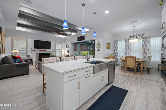 kitchen with a center island with sink, pendant lighting, white cabinets, and a sink