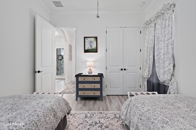 bedroom with crown molding, a closet, and light wood-type flooring