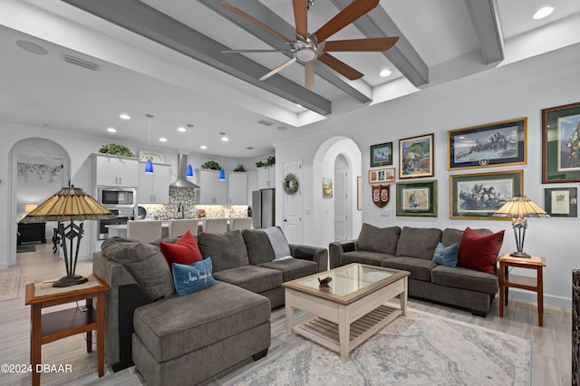 living room with ceiling fan, beam ceiling, light wood-type flooring, and ornamental molding