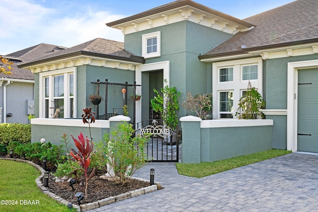 view of front of house featuring a fenced front yard, a gate, roof with shingles, and stucco siding