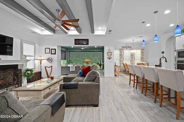 living room with beamed ceiling, ceiling fan, light hardwood / wood-style floors, and crown molding