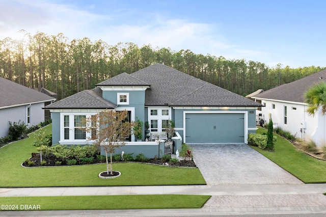 view of front of house with decorative driveway, stucco siding, a shingled roof, a front yard, and a garage