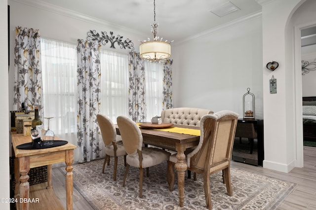 dining area featuring light wood-style floors, baseboards, arched walkways, and ornamental molding