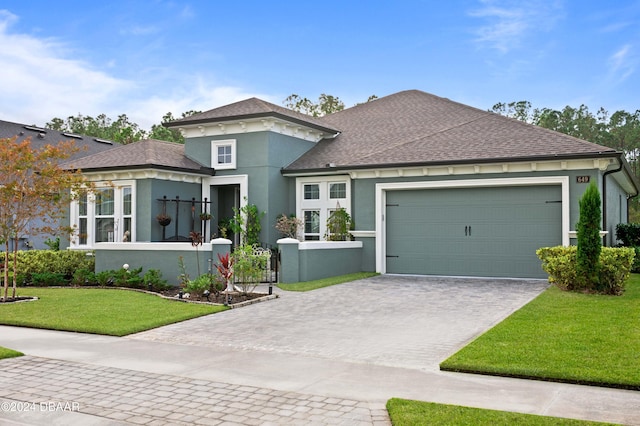 view of front of home featuring a garage, decorative driveway, a front lawn, and stucco siding