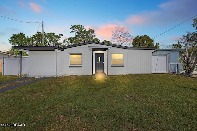 view of front of house with concrete block siding, a front yard, and fence