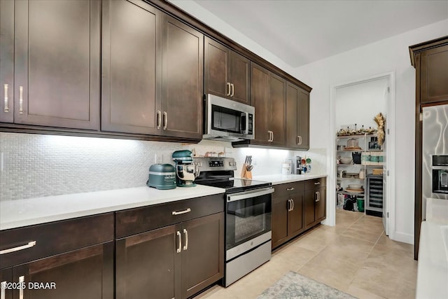 kitchen with decorative backsplash, light countertops, dark brown cabinetry, and stainless steel appliances