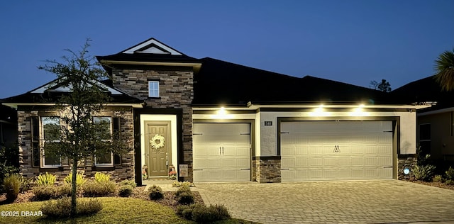 view of front of property featuring stone siding, decorative driveway, and a garage