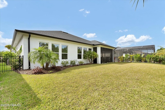 rear view of house featuring a lawn, fence, a sunroom, and stucco siding