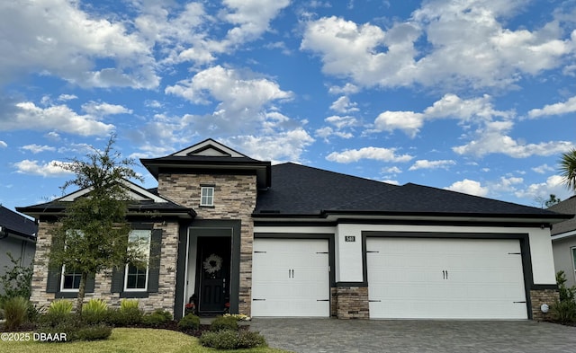 view of front of house with stucco siding, decorative driveway, stone siding, an attached garage, and a shingled roof