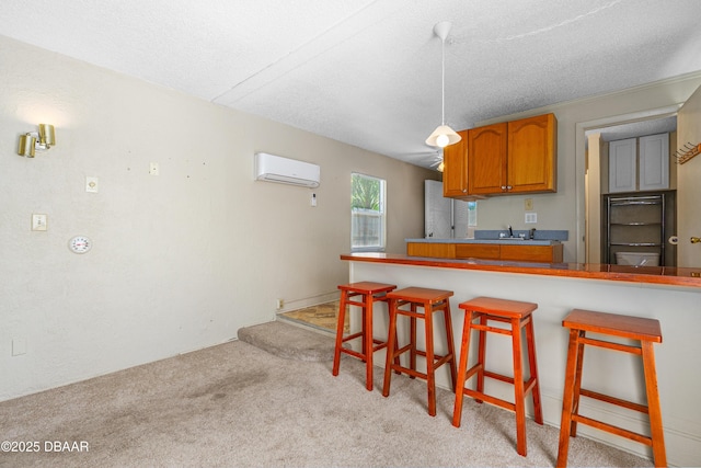 1104 Jacaranda Ave, Daytona Beach, FL 32118 - kitchen with a wall unit AC, brown cabinets, a breakfast bar, light colored carpet, and a textured ceiling