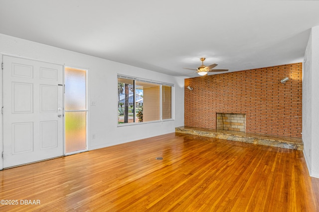 1104 Jacaranda Ave, Daytona Beach, FL 32118 - unfurnished living room featuring wood finished floors, a ceiling fan, a fireplace, and brick wall