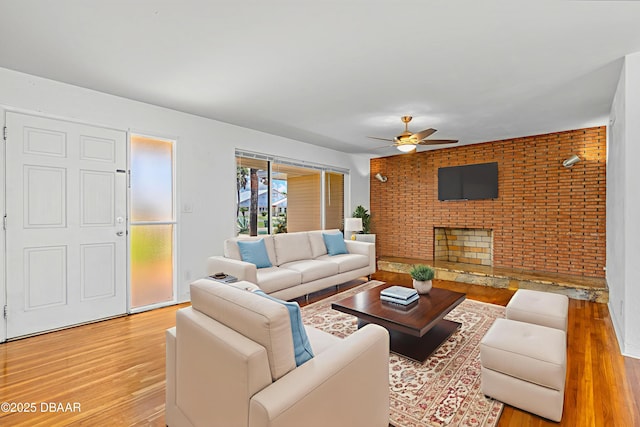1104 Jacaranda Ave, Daytona Beach, FL 32118 - living room featuring light wood finished floors, ceiling fan, brick wall, and a fireplace