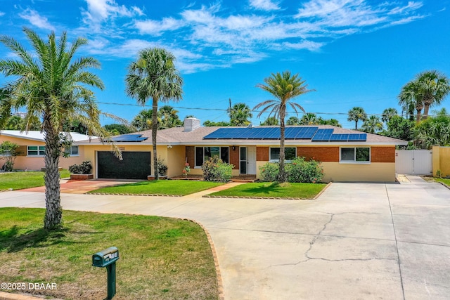 1104 Jacaranda Ave, Daytona Beach, FL 32118 - ranch-style home with driveway, a gate, solar panels, a chimney, and brick siding