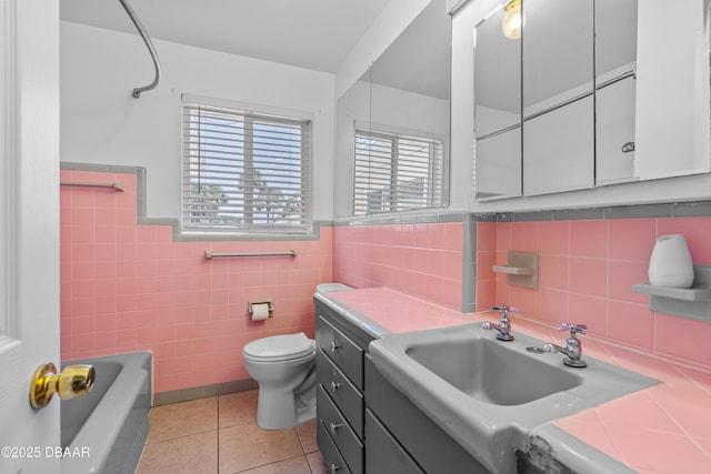 1104 Jacaranda Ave, Daytona Beach, FL 32118 - bathroom with tile patterned flooring, a bath, tile walls, vanity, and a wainscoted wall