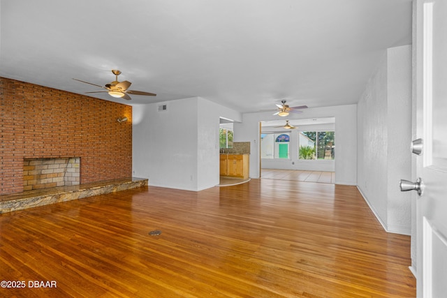1104 Jacaranda Ave, Daytona Beach, FL 32118 - unfurnished living room featuring ceiling fan, light wood-style floors, and a fireplace