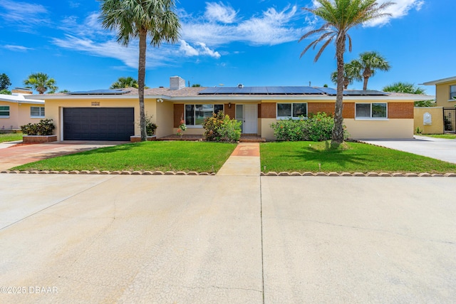 1104 Jacaranda Ave, Daytona Beach, FL 32118 - ranch-style house featuring a front lawn, driveway, a garage, and solar panels