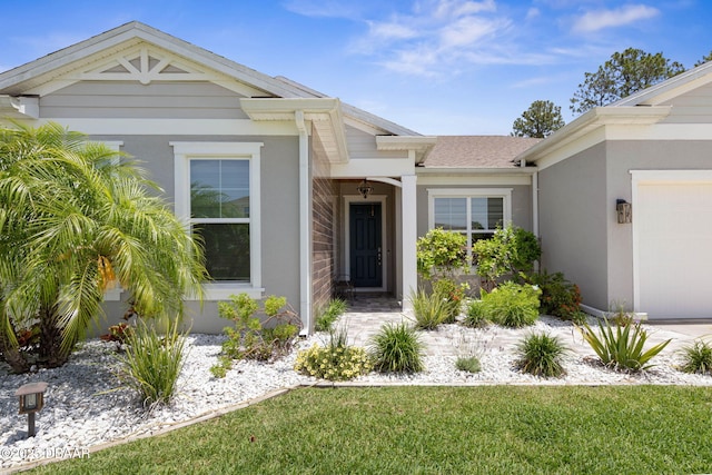 75 Trailmark Ct, Ormond Beach, FL 32174 - view of exterior entry with stucco siding, a garage, and roof with shingles