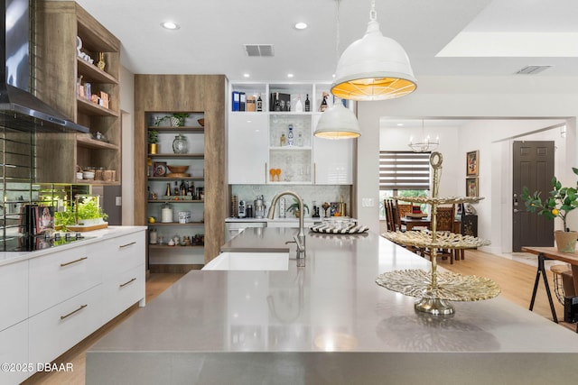 75 Trailmark Ct, Ormond Beach, FL 32174 - kitchen with open shelves, wall chimney range hood, black stovetop, modern cabinets, and white cabinetry