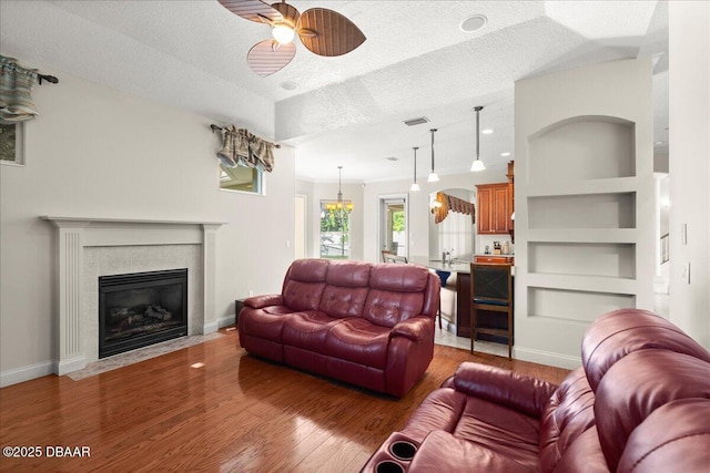 36 Allenwood Look, Ormond Beach, FL 32174 - living room with ceiling fan, wood finished floors, a tile fireplace, a textured ceiling, and built in features