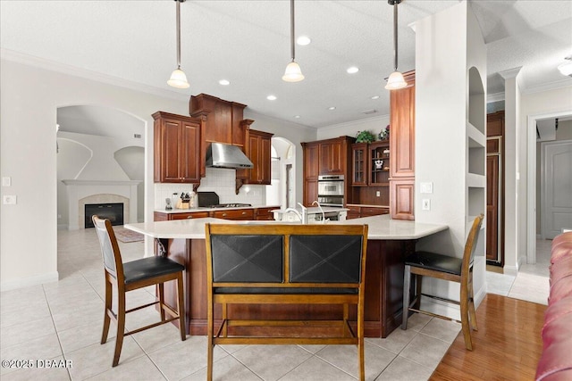 36 Allenwood Look, Ormond Beach, FL 32174 - kitchen with under cabinet range hood, ornamental molding, light countertops, backsplash, and a kitchen breakfast bar