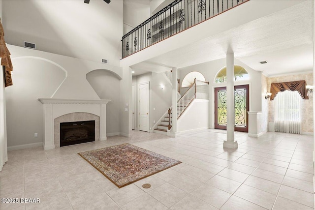 36 Allenwood Look, Ormond Beach, FL 32174 - unfurnished living room featuring tile patterned floors, a high ceiling, stairs, a tile fireplace, and a ceiling fan