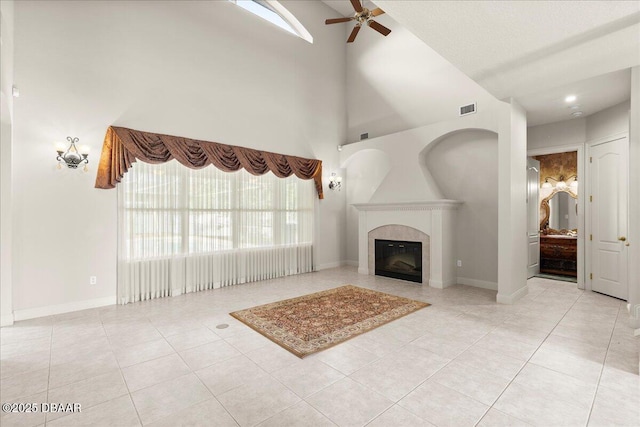 36 Allenwood Look, Ormond Beach, FL 32174 - unfurnished living room featuring ceiling fan, a towering ceiling, light tile patterned floors, and a tiled fireplace