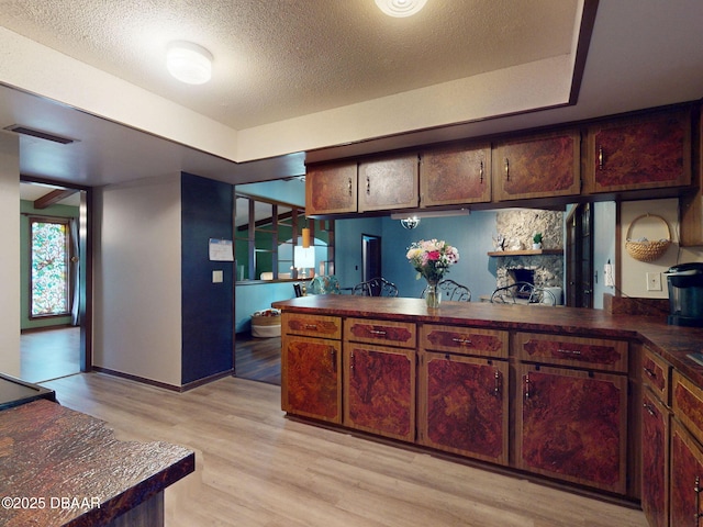 108 Dee St, New Smyrna Beach, FL 32168 - kitchen with dark countertops, light wood-style floors, a textured ceiling, baseboards, and a peninsula