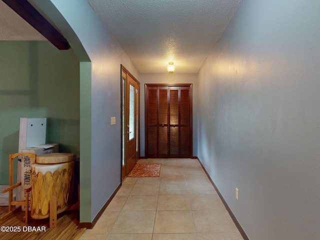 108 Dee St, New Smyrna Beach, FL 32168 - hall featuring a textured ceiling, arched walkways, baseboards, and light tile patterned floors