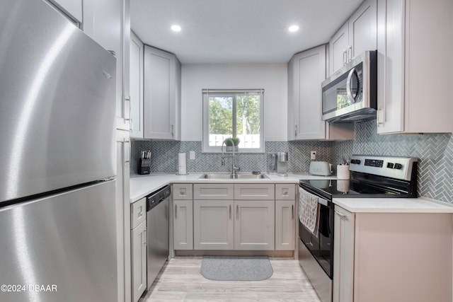 kitchen featuring light hardwood / wood-style floors, sink, appliances with stainless steel finishes, and tasteful backsplash