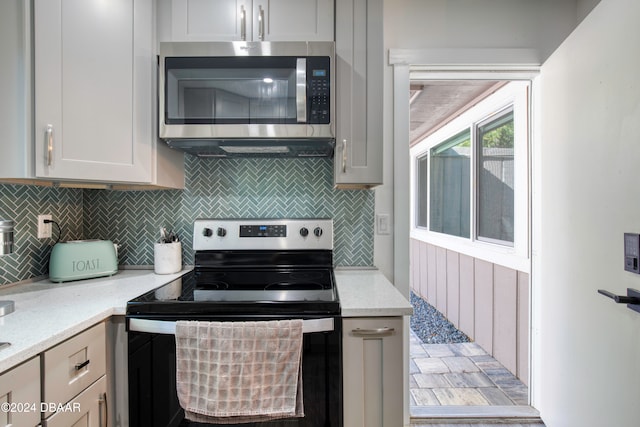 kitchen with backsplash, light stone countertops, and stainless steel appliances