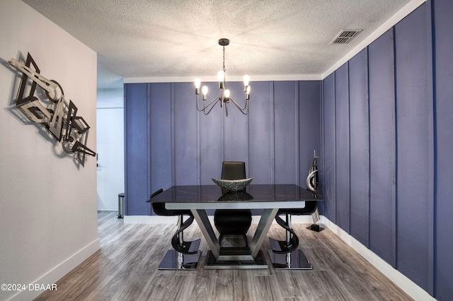 dining room with hardwood / wood-style flooring, a textured ceiling, and a chandelier