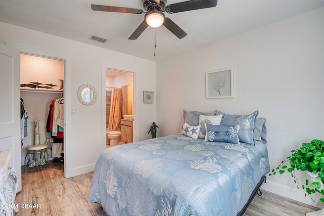 bedroom featuring ensuite bath, ceiling fan, light hardwood / wood-style flooring, a walk in closet, and a closet