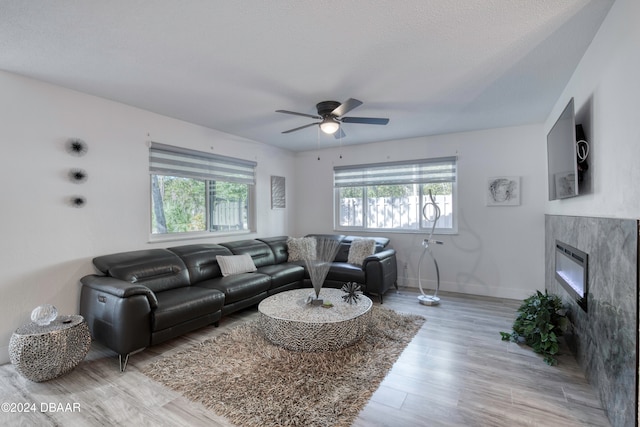 living room with a wealth of natural light, ceiling fan, light hardwood / wood-style floors, and a textured ceiling