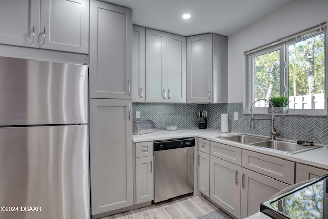 kitchen with decorative backsplash, light wood-type flooring, sink, and appliances with stainless steel finishes