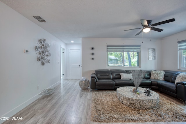 living room with hardwood / wood-style floors, ceiling fan, and a textured ceiling