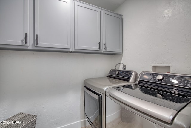 laundry room featuring washer and clothes dryer and cabinets