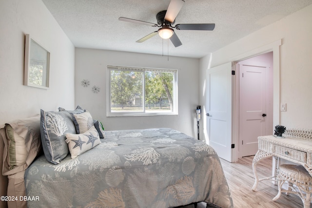 bedroom featuring a textured ceiling, light wood-type flooring, and ceiling fan