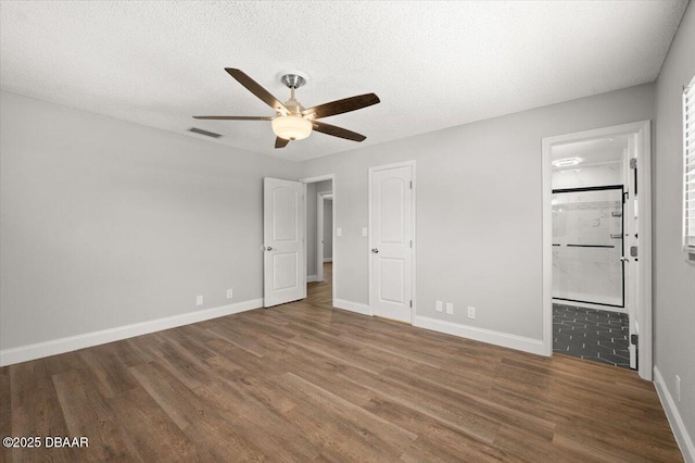 14 Woodlake Dr, Port Orange, FL 32129 - unfurnished bedroom featuring wood finished floors, baseboards, a textured ceiling, connected bathroom, and a ceiling fan