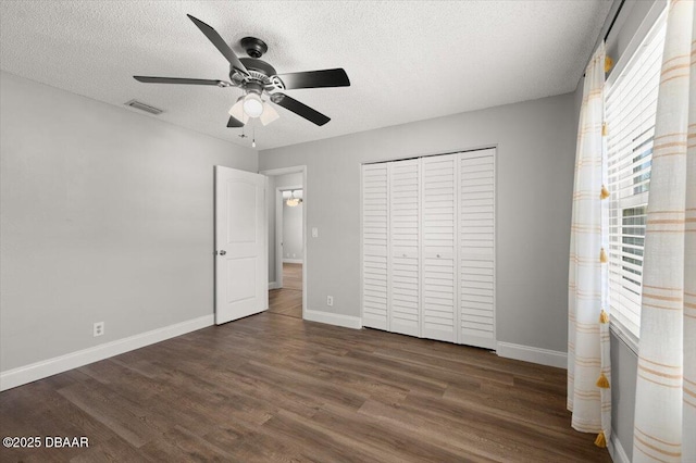 14 Woodlake Dr, Port Orange, FL 32129 - unfurnished bedroom with a textured ceiling, dark wood-style flooring, baseboards, a closet, and ceiling fan