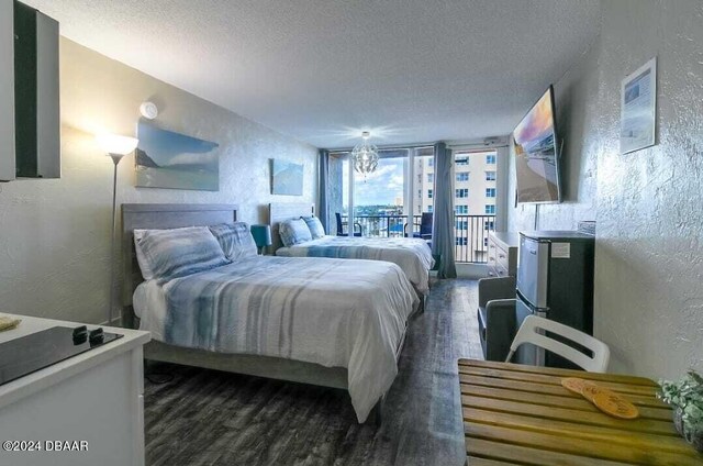 3501 S Atlantic Ave Unit 503, Daytona Beach, FL 32118 - bedroom with a textured wall, dark wood finished floors, a textured ceiling, and access to outside