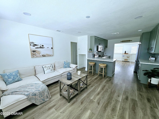 living area with wood finished floors, a textured ceiling, recessed lighting, and baseboards