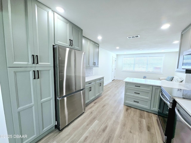 kitchen featuring appliances with stainless steel finishes, gray cabinetry, light wood-type flooring, light countertops, and recessed lighting