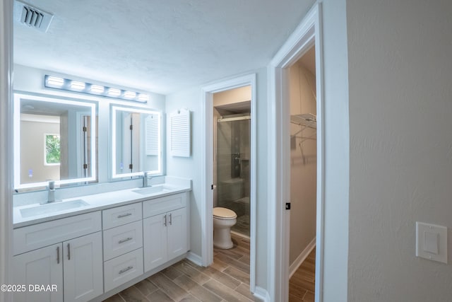 15 Misners Trl, Ormond Beach, FL 32174 - full bathroom featuring a stall shower, double vanity, a walk in closet, toilet, and wood finish floors