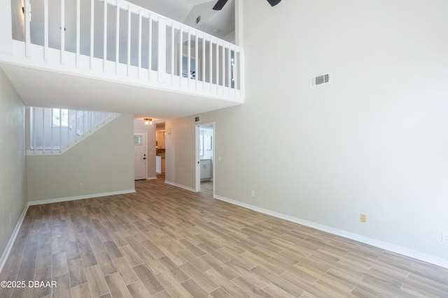 15 Misners Trl, Ormond Beach, FL 32174 - unfurnished living room with a ceiling fan, baseboards, light wood finished floors, a towering ceiling, and stairs