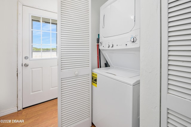 clothes washing area with light hardwood / wood-style floors and stacked washer and clothes dryer