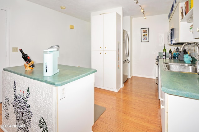 kitchen featuring white cabinets, light wood-type flooring, sink, and appliances with stainless steel finishes